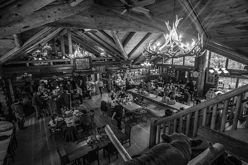 Monochrome indoor shot of a "lumberjack restaurant" with antler chandoliers and big wooden posts.
