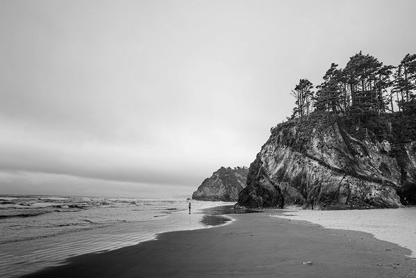 Sea cliffs. A lone figure stands at their base.