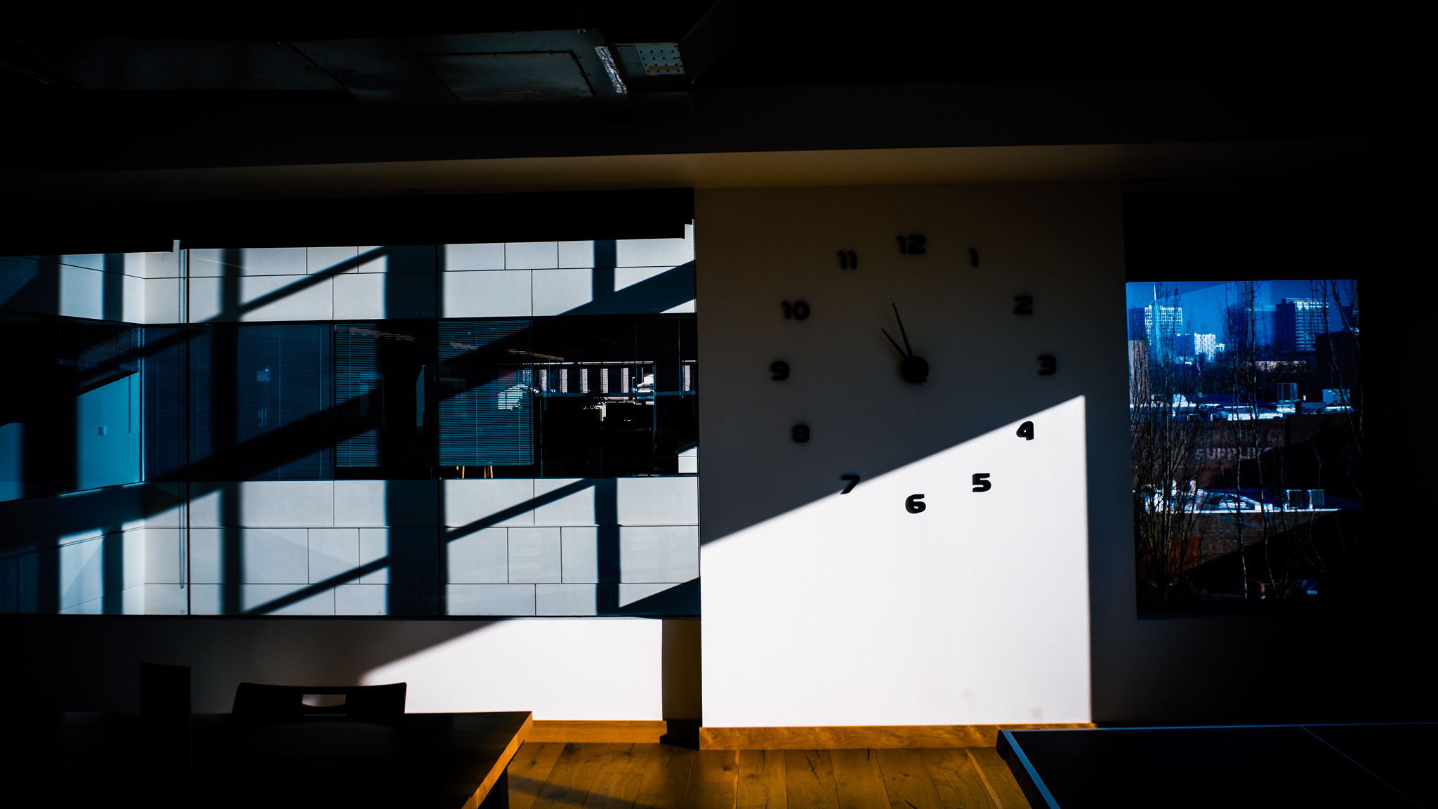 A clock built into a wall is in sharp, dark shadows.