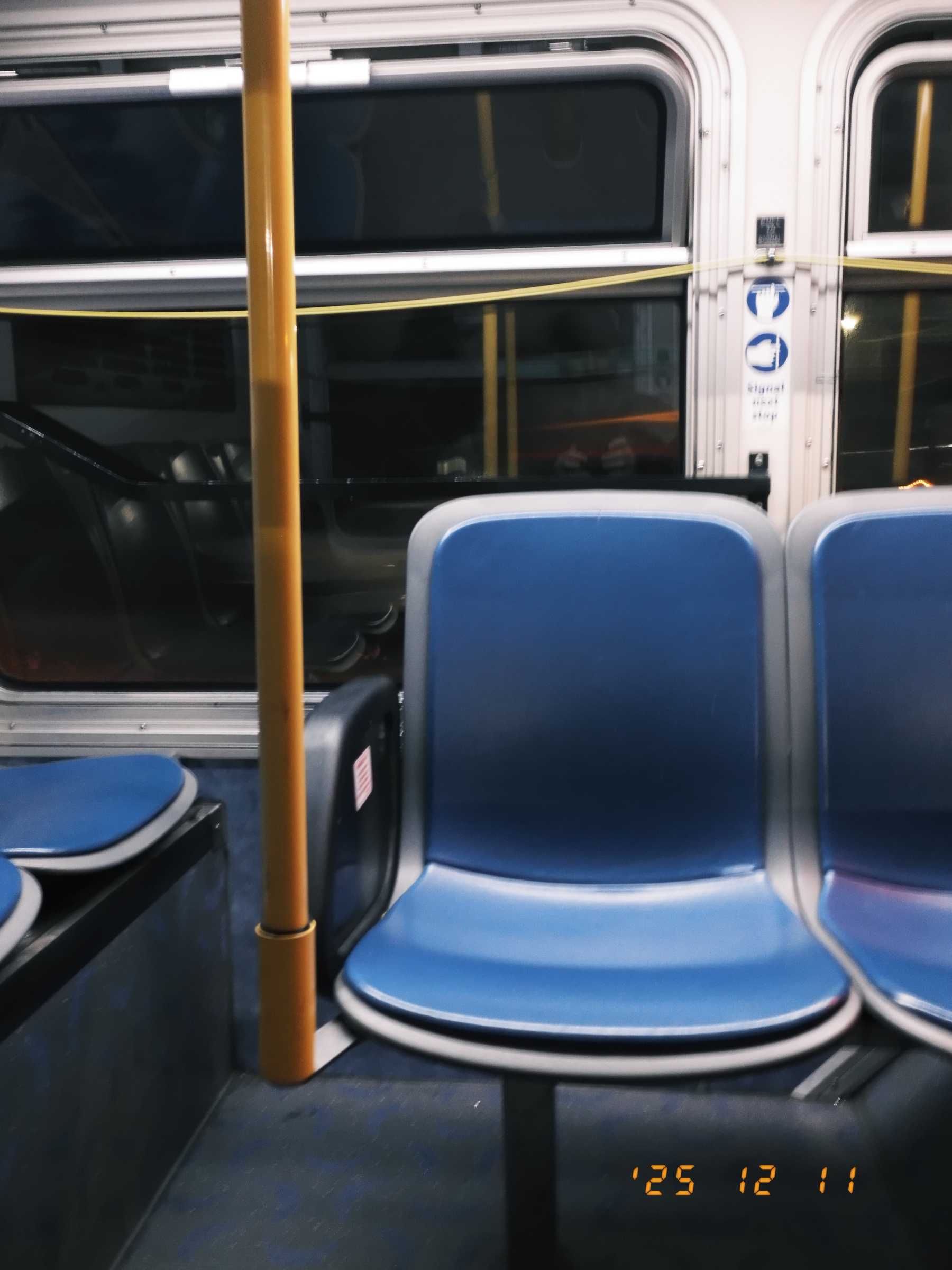 Two empty blue seats on a bus with a window in the background.